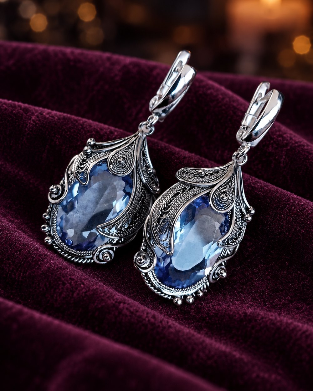 Pair of blue filigree drop earrings lying on velvet