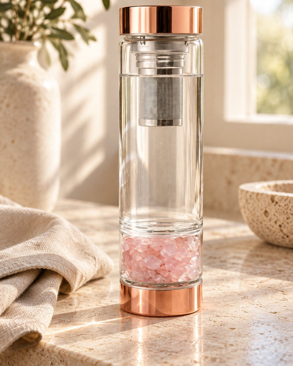 Crystal Elixir Water Bottle with rose quartz chips on a kitchen counter