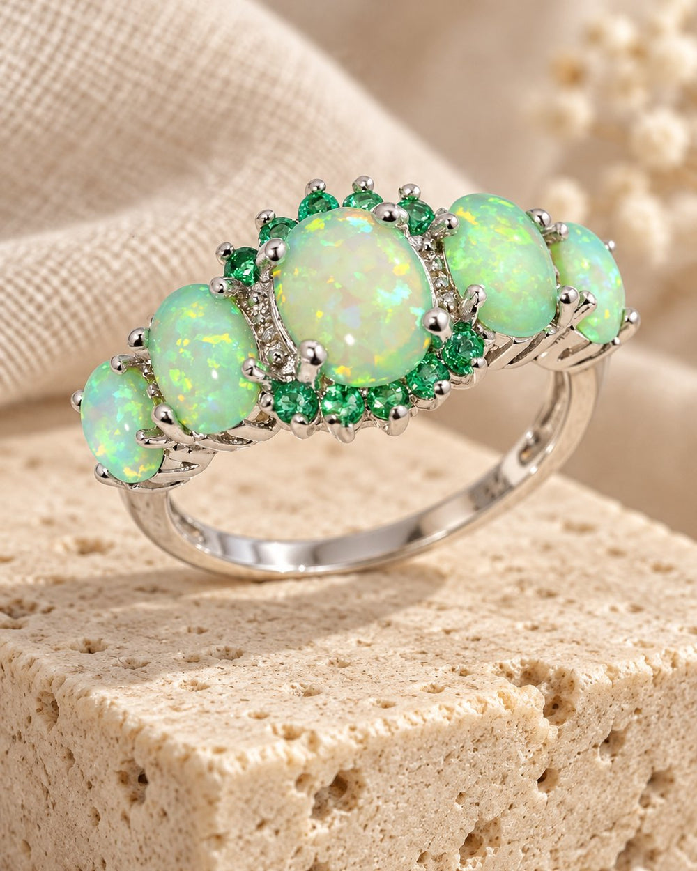 Green Fire Opal & Emerald Ring on a travertine block