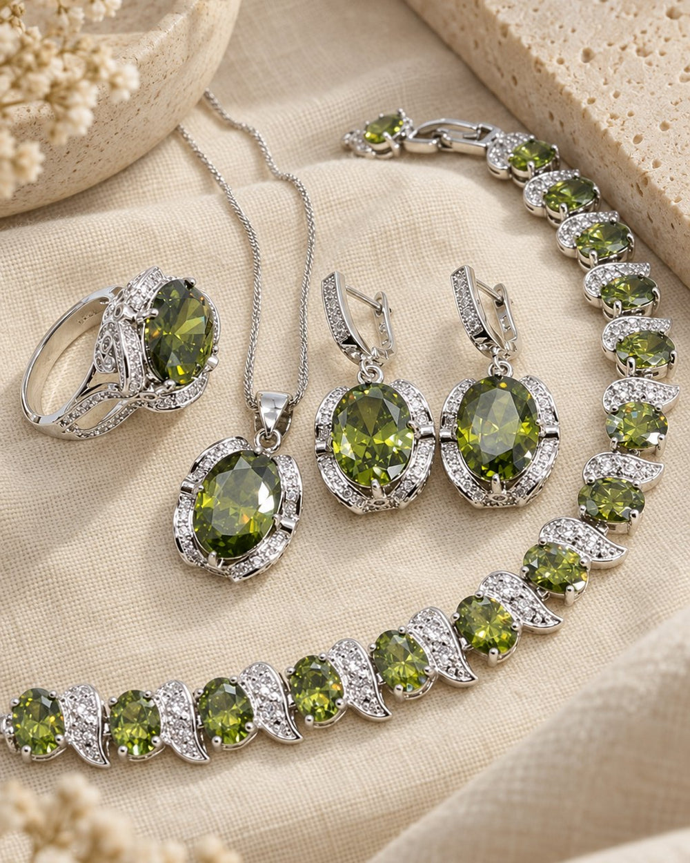 Green oval halo jewelry set laid out on cream linen