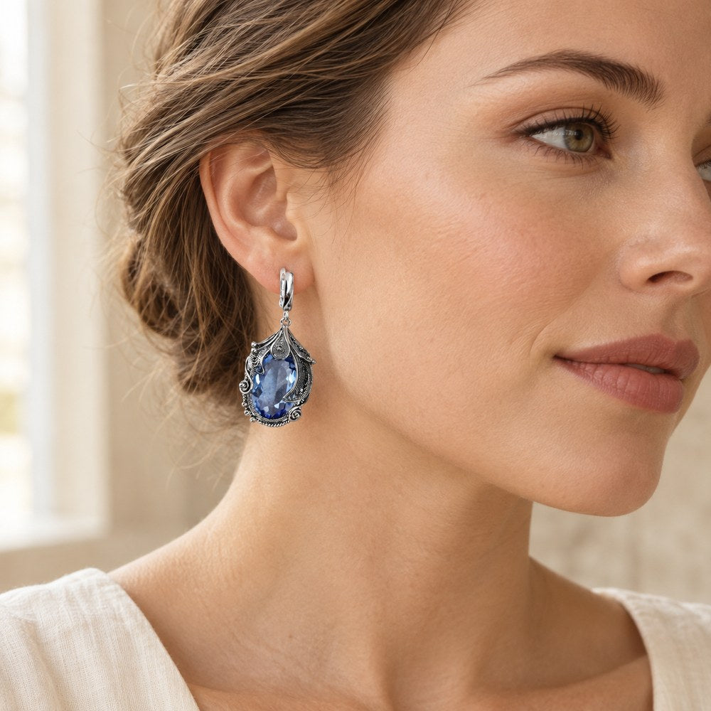 Blue filigree drop earring worn by a woman, seen in profile