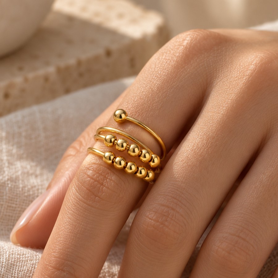 Gold-tone triple coil bead spinner ring worn on a woman's finger