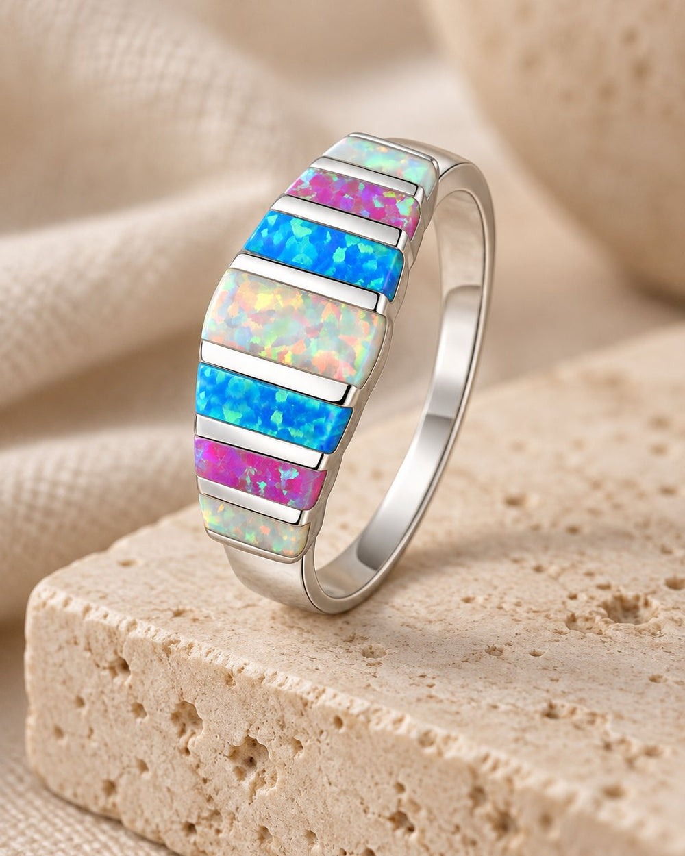 Blue & White Fire Opal Ring standing on a travertine block