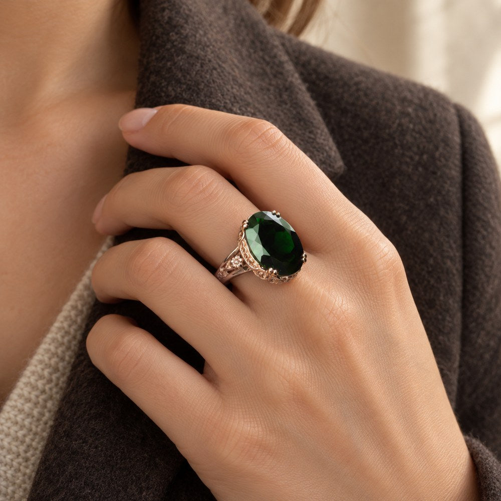 Carved filigree cocktail ring with a deep green stone, worn on a woman's finger