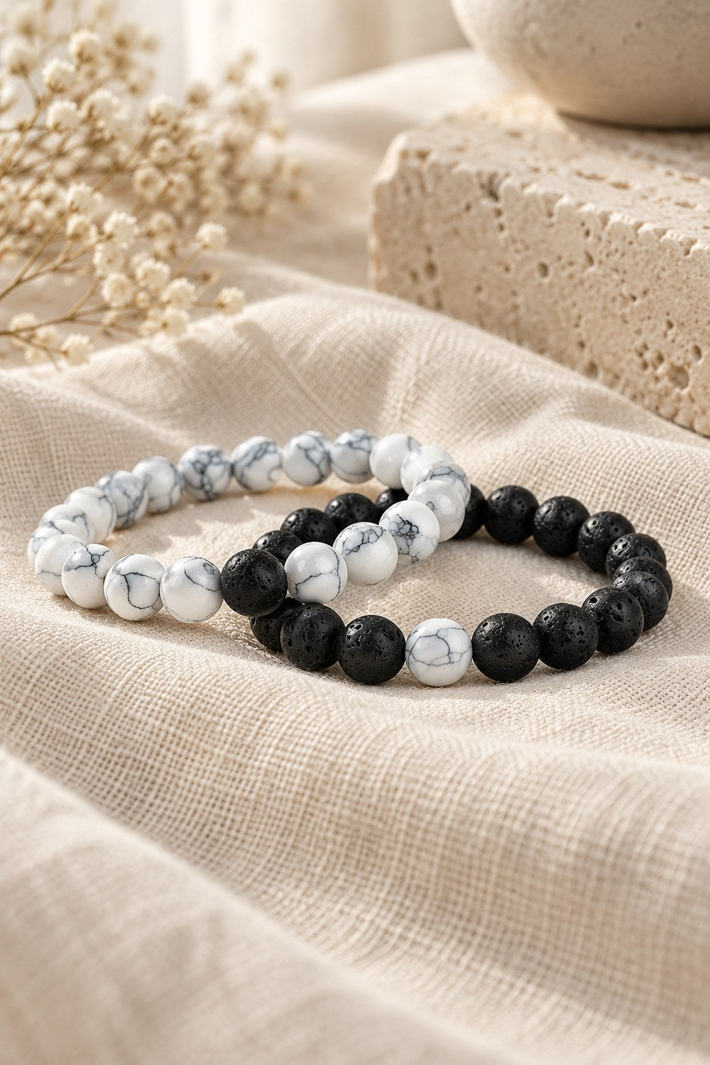 White howlite and black lava bead bracelets side by side on linen