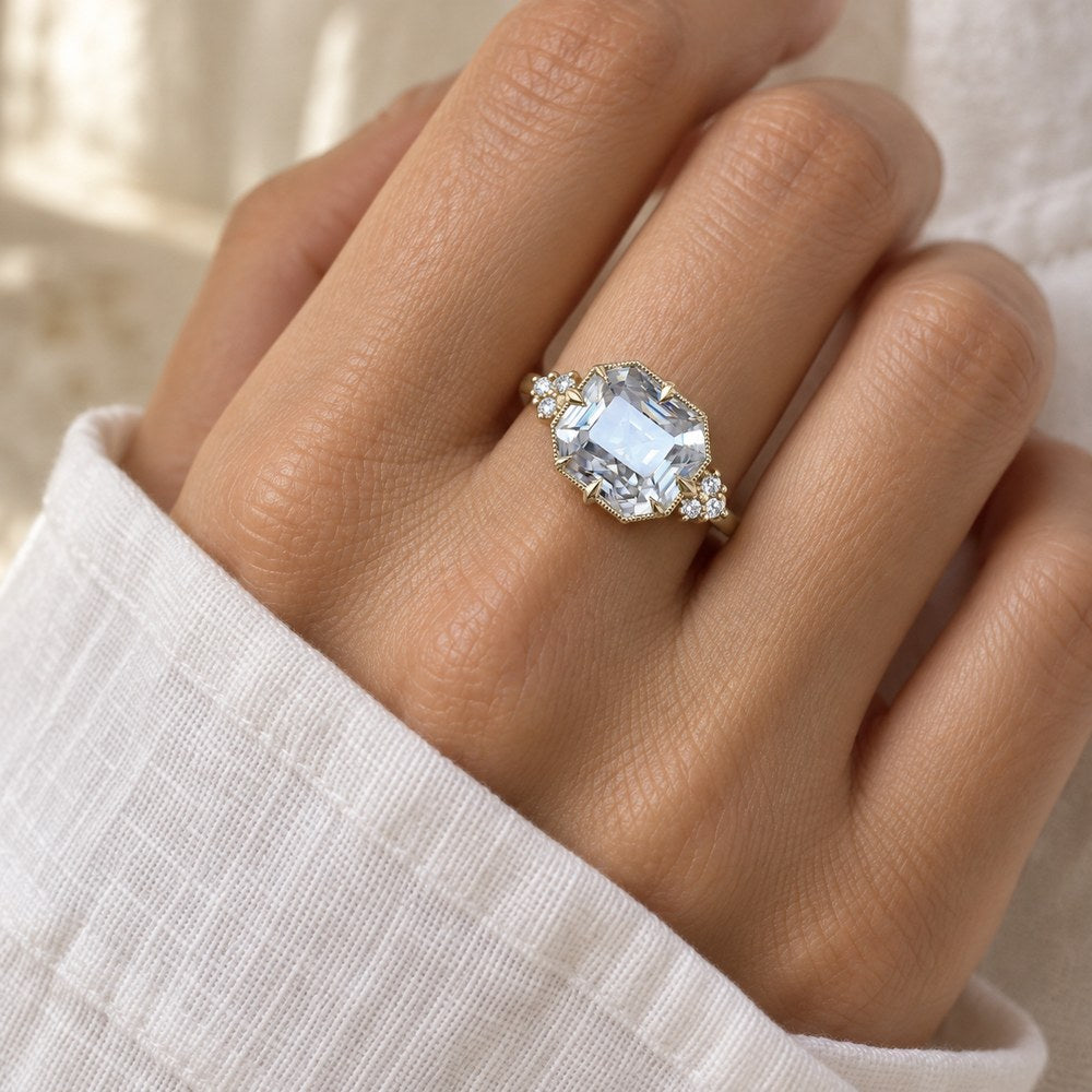 Emerald-cut simulated diamond ring in gold-tone, worn on a woman's finger