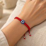 Red string evil eye bracelet with a blue nazar bead, worn on a woman's wrist