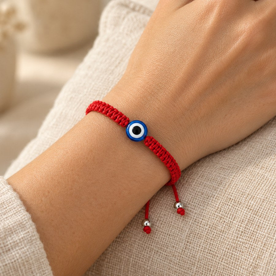 Red string evil eye bracelet with a blue nazar bead, worn on a woman's wrist
