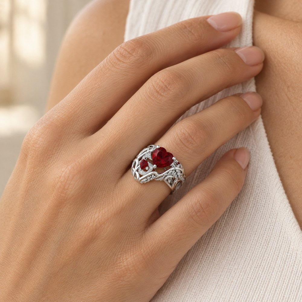Feathered Heart Cocktail Ring with a red heart stone worn on a woman's ring finger