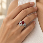 Feathered Heart Cocktail Ring with a red heart stone worn on a woman's ring finger