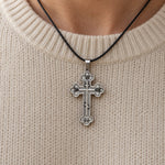 IC XC NIKA Orthodox cross pendant on a black cord, worn over a cream sweater