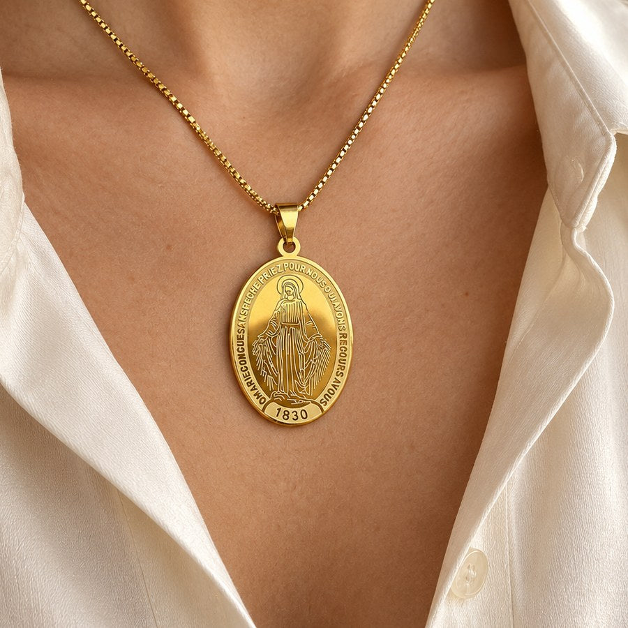 Gold-tone oval Miraculous Medal necklace worn with a cream silk blouse