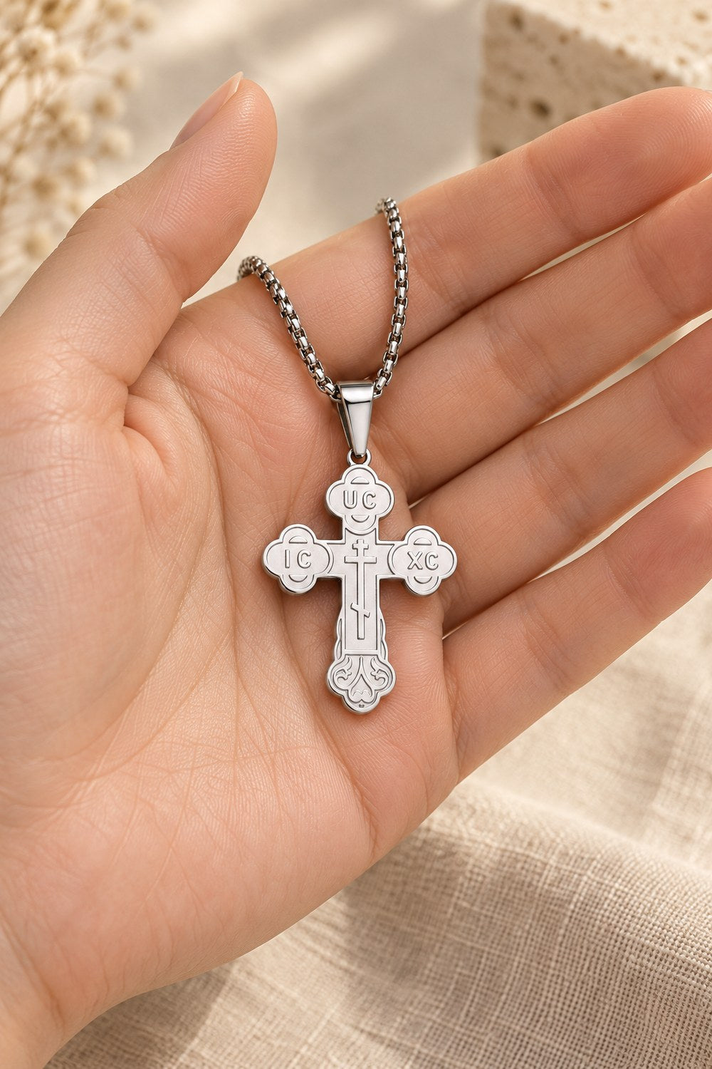 Orthodox crucifix pendant on its chain, resting in an open palm