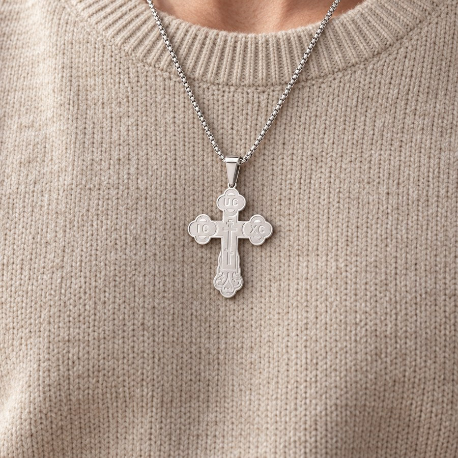 Silver-tone Orthodox crucifix necklace worn over an oatmeal sweater