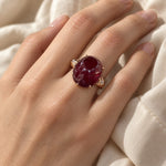 Oval simulated-ruby ring in rose gold-tone, worn on a woman's finger