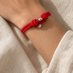 Thin red string bracelet with a sliding knot, worn on the left wrist