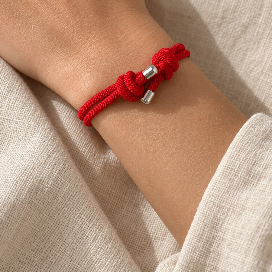 Thin red string bracelet with a sliding knot, worn on the left wrist