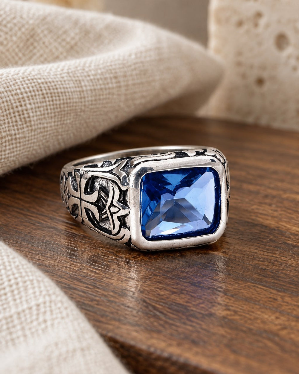 Sapphire-blue signet ring on a walnut surface