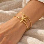 Starfish Double-Layer Cuff in gold color, worn on a woman's wrist