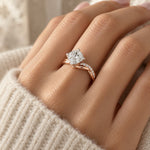 Twisted band solitaire ring in rose gold tone, worn on a woman's finger